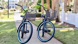 Two bicycles with baskets on a sidewalk.