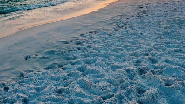 A beach with waves and a sunset.