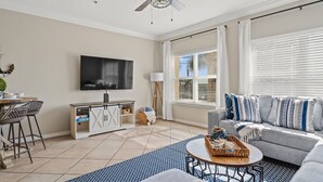 A living room with a TV, sofa, coffee table, and a ceiling fan.