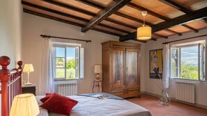 A bedroom with a bed, two windows, a radiator, a wooden cabinet, and a hanging lamp. - Wonderful private villa with A/C, private pool, WIFI, TV and panoramic view, close to San Gimign... (Gambassi Terme)