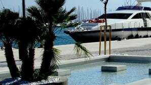 A marina with boats, a pool area with concrete steps, and palm trees. - Luxury spacious studio in the heart of Split (Split)