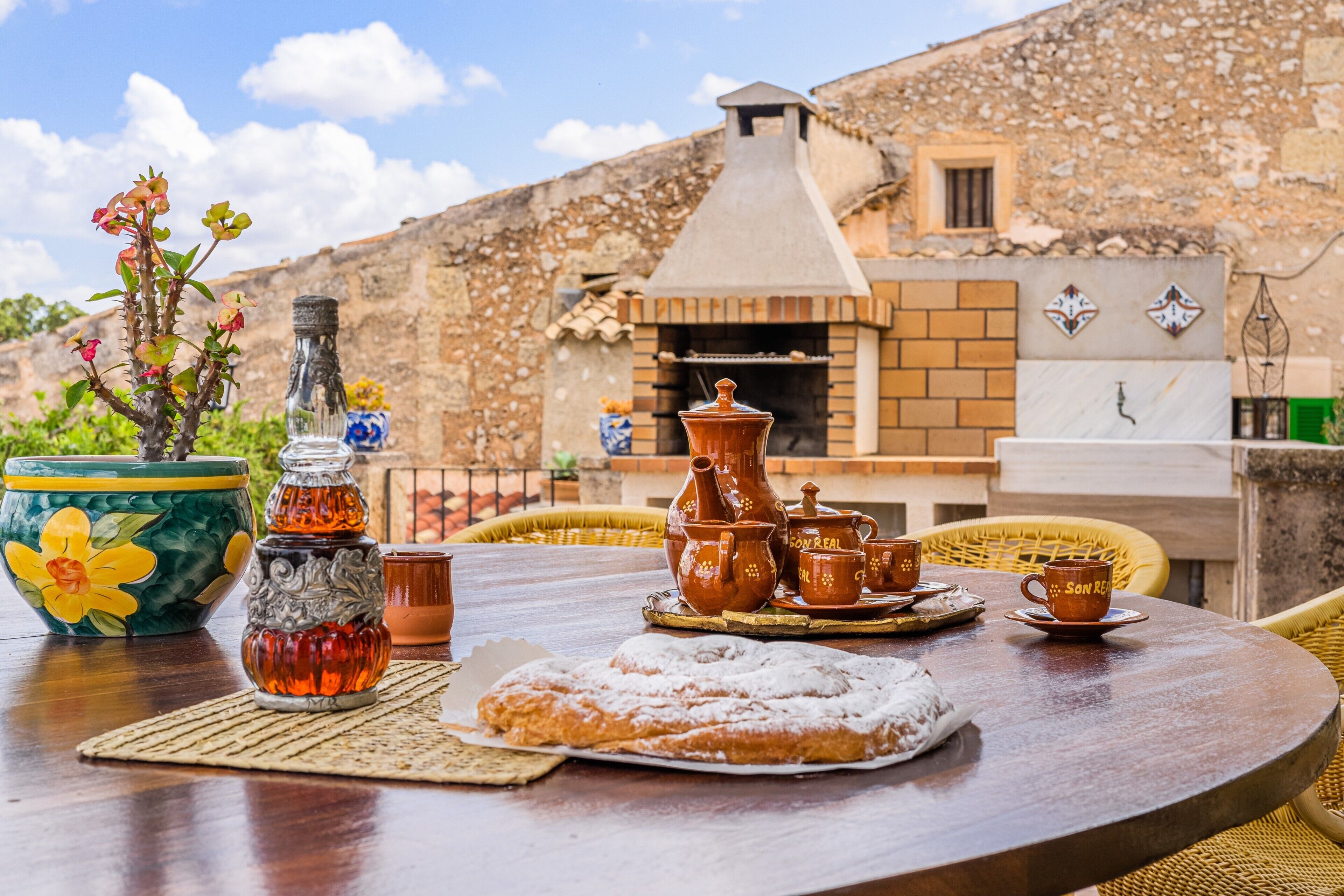 A table set with traditional pottery, a dessert, and a potted plant.
