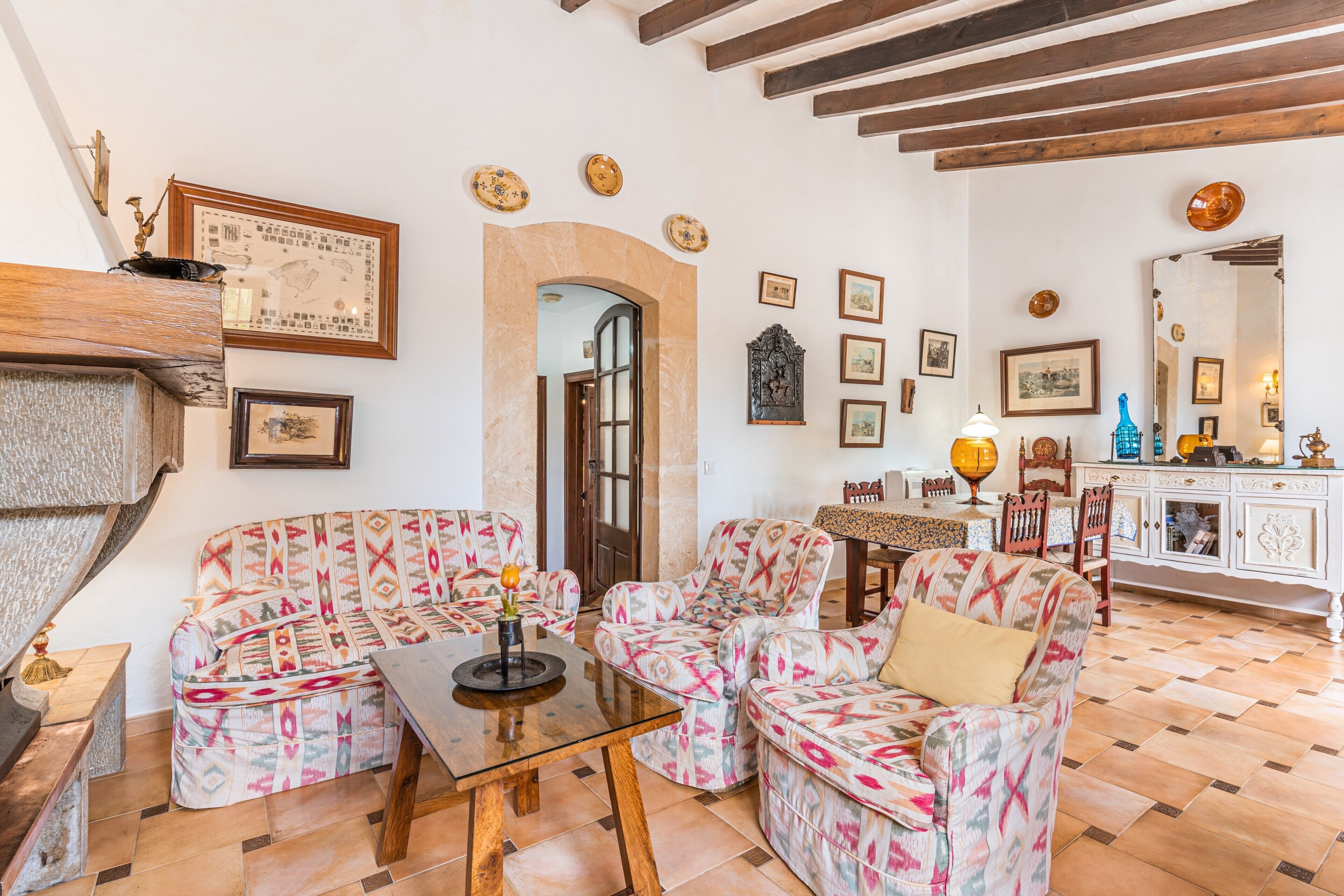 A living room with patterned sofas, a glass coffee table, and a fireplace.