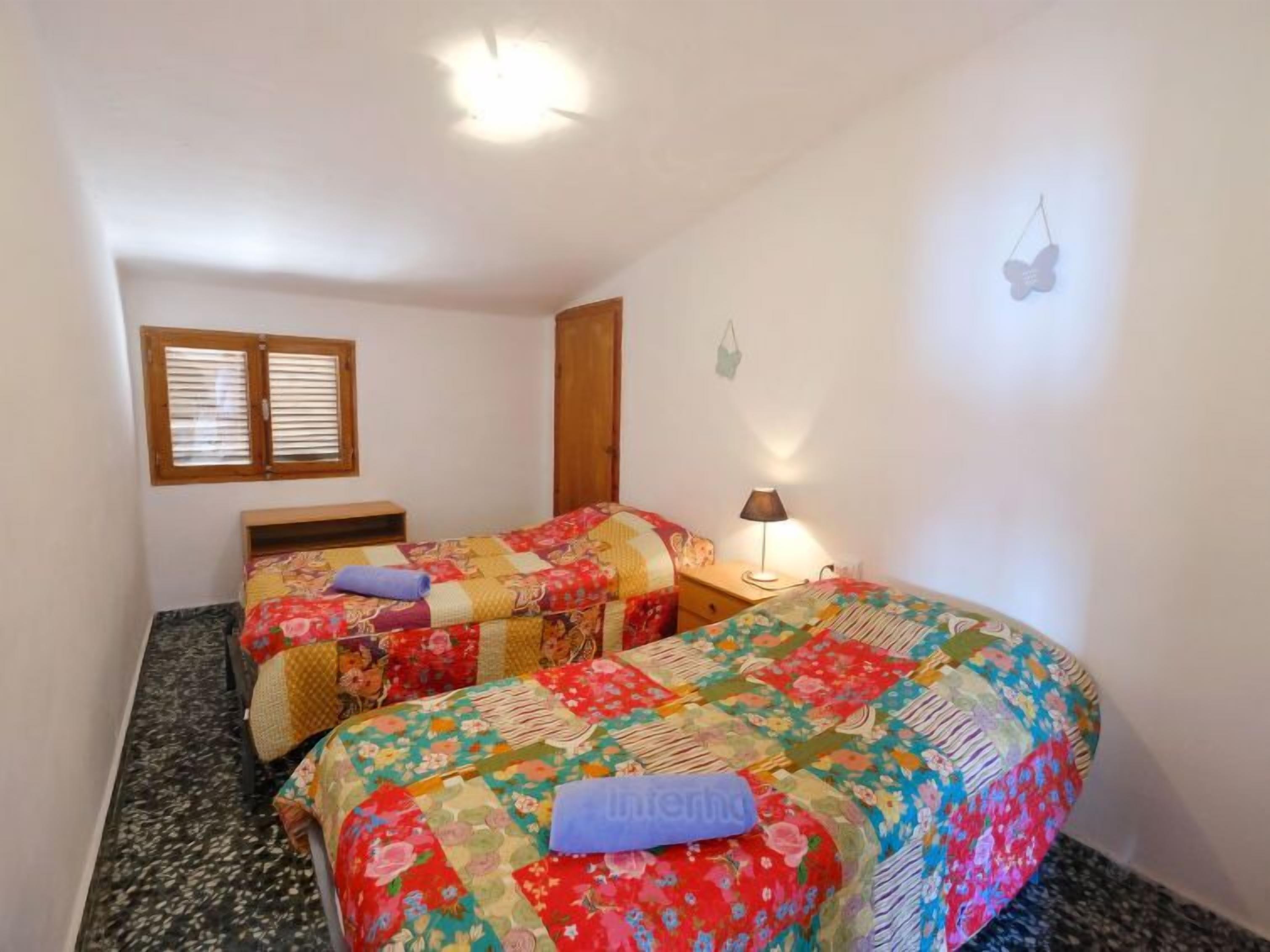 A bedroom with two beds, a window, a lamp, and a butterfly decoration.