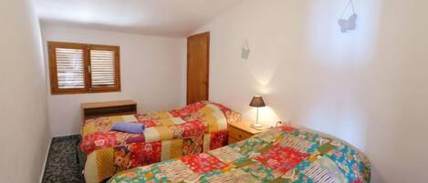 A bedroom with two beds, a window, a lamp, and a butterfly decoration.