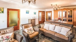 A cozy living room with a large sofa, a wooden cabinet, and a chandelier.