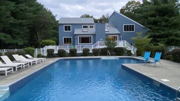 A swimming pool with lounge chairs and a building in the background.
