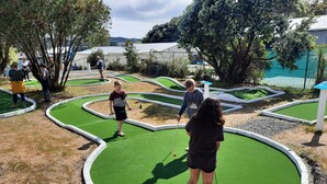 A miniature golf course with multiple green putting areas and a water hazard. - Walking distance to cafes and restaurants (Mangawhai)