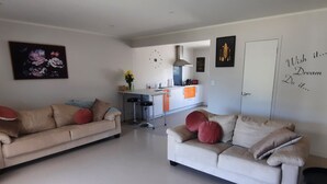A modern living room with two sofas, a kitchen in the background, and a motivational wall quote. - Walking distance to cafes and restaurants (Mangawhai)