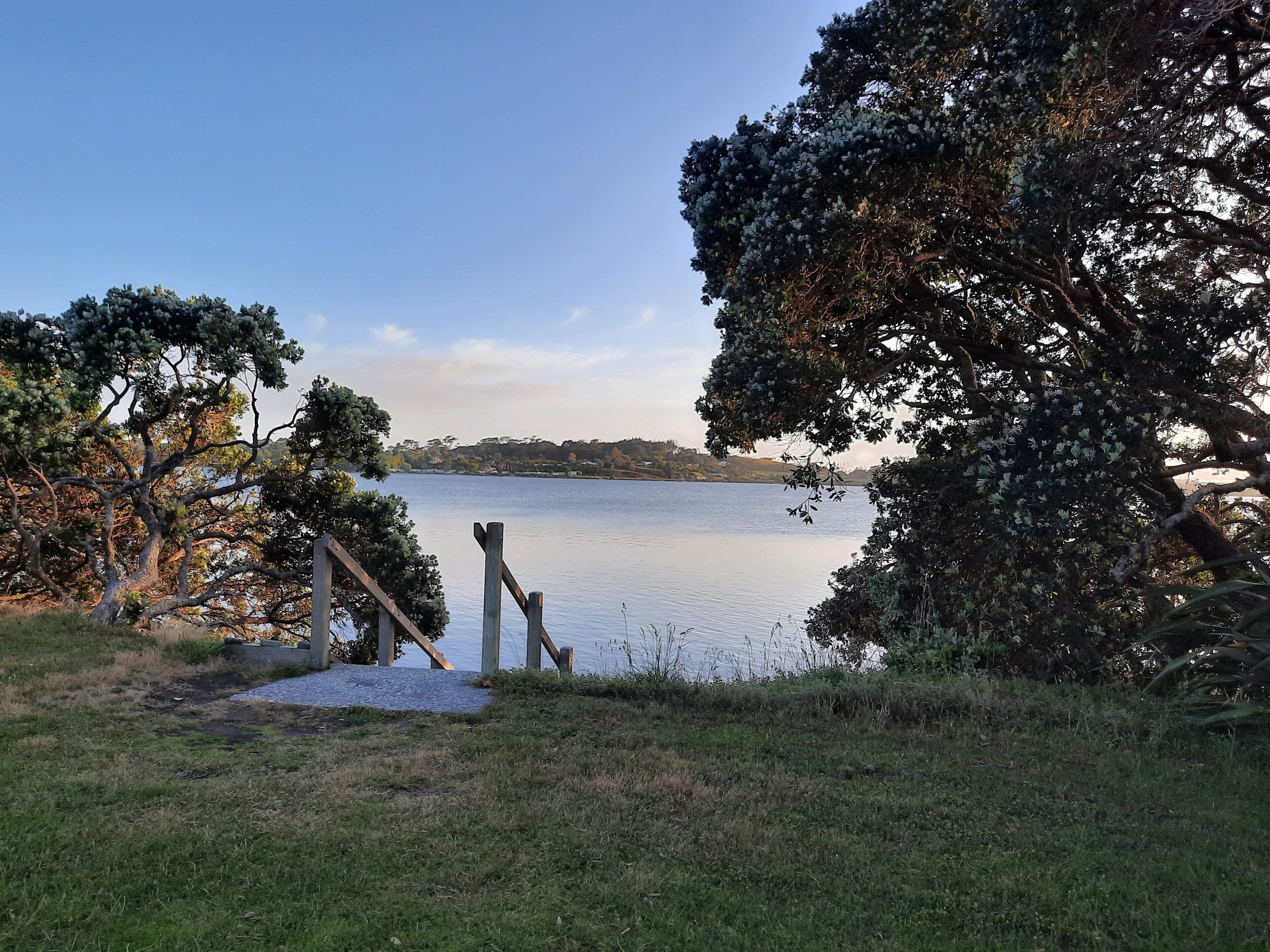A lakeside view with a wooden dock and trees.