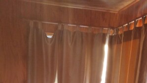 Ein Zimmer mit einer dunkelbraunen Ledersofa, einem Fliesenboden und Holzwänden.