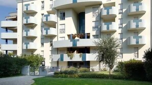 Un edificio moderno de varios pisos con balcones, un patio central y un jardín bien cuidado.