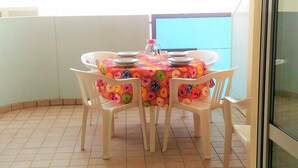 Comedor con una mesa dispuesta para cuatro personas, rodeada de sillas de plástico, sobre piso de baldosas.
