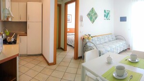 Una habitación de hotel compacta con kitchenette, comedor y cama.