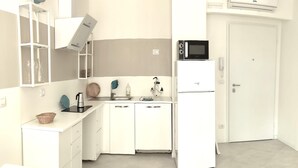 Cocina compacta con gabinetes blancos, microondas y refrigerador.