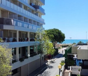 A multi-story hotel with balconies, a clear view of the sea, and a pedestrian pathway. - Two-room apartment 50 metres from the beach (Bibione)