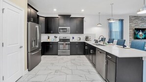 Una cocina moderna con armarios oscuros, electrodom ésticos de acero inoxidable y piso de mármol.