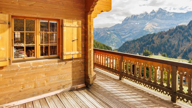 Een houten chalet met een balkon met uitzicht op een bergachtig landschap.