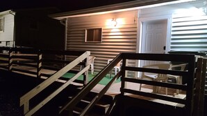 A wooden staircase leading to a house with a porch, a door, and a small window.