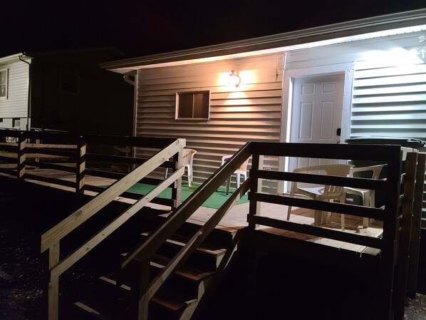 A wooden staircase leading to a house with a porch, a door, and a small window.
