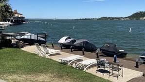 A waterfront view with a dock, lounge chairs, and a covered area with a jet ski.
