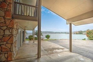 A covered outdoor area with a stone wall, a balcony, and a view of a lake.