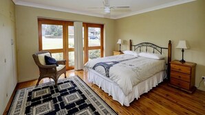 A bedroom with a bed, a chair, a nightstand, and a ceiling fan. - Retreat on Gleeson (Forster)