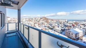 A balcony with a clear view of a snow-covered town and the sea. - Glow (Otaru)