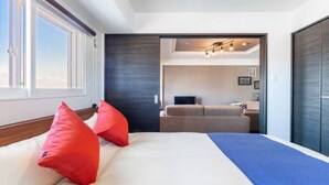 A modern hotel room with a large bed, a sofa, and a TV. There is a window providing natural light and a view of the sky. - Glow (Otaru)