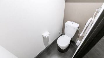 Ein kleines, modernes Badezimmer mit Toilette, Handtuchhalter und dunklem Boden.