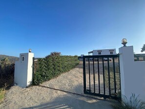 Enter a serene retreat through the gated entrance, surrounded by lush greenery and rolling hills.