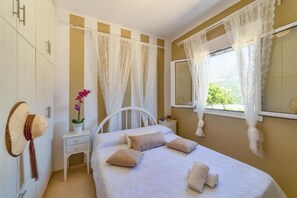 Relax in a serene bedroom with a large bed, nightstand, and a beautiful view through the large window.