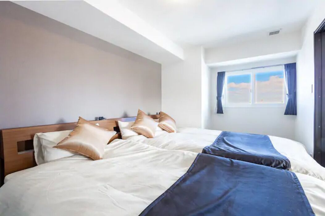 A hotel room with a large bed, a wooden headboard, and a window with curtains.