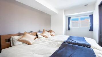 A hotel room with a large bed, a wooden headboard, and a window with curtains.