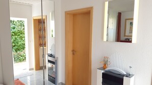 A modern bedroom with a glass door leading to a balcony, a wooden door, and a small table with a vase. - HAUS Toscana - 350 m to the beach, terrace/garden - Holiday home Toscana (Koserow)