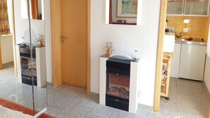 A room with a fireplace, a door, a mirror, and a kitchen area. - HAUS Toscana - 350 m to the beach, terrace/garden - Holiday home Toscana (Koserow)