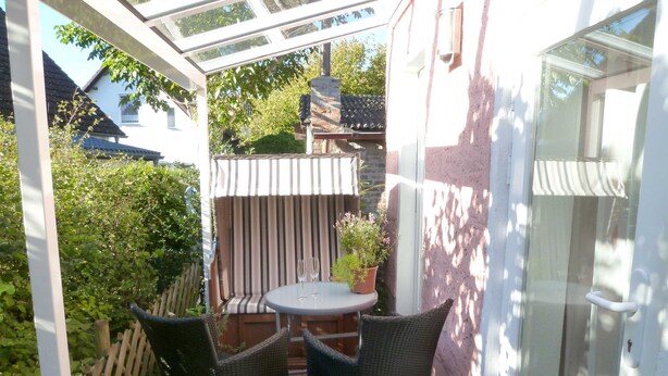 A small patio with a round table and two wicker chairs, a potted plant, and a striped cushion. - HAUS Toscana - 350 m to the beach, terrace/garden - Holiday home Toscana (Koserow)