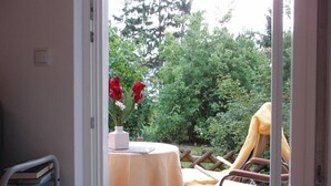 A patio with a table, chairs, and a vase of red flowers. - HAUS Toscana - 350 m to the beach, terrace/garden - Holiday home Toscana (Koserow)