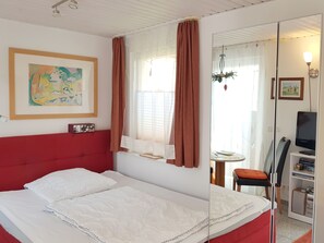Une chambre d’hôtel comprenant un lit, un bureau avec une chaise, une télévision et une bibliothèque.