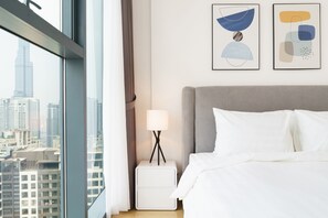 Une chambre d’hôtel avec un lit, une table de chevet avec une lampe et deux tableaux abstraits accrochés au mur.