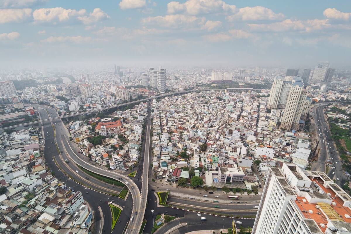An aerial view of a densely populated urban area with multiple high-rise buildings, a complex road network, and a mix of residential and commercial structures.