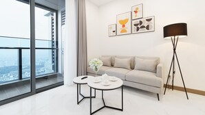 A modern living room with a sofa, two round tables, a floor lamp, and artwork on the wall. - Hoasun Skyview Sunwah Pearl (Ho Chi Minh City)