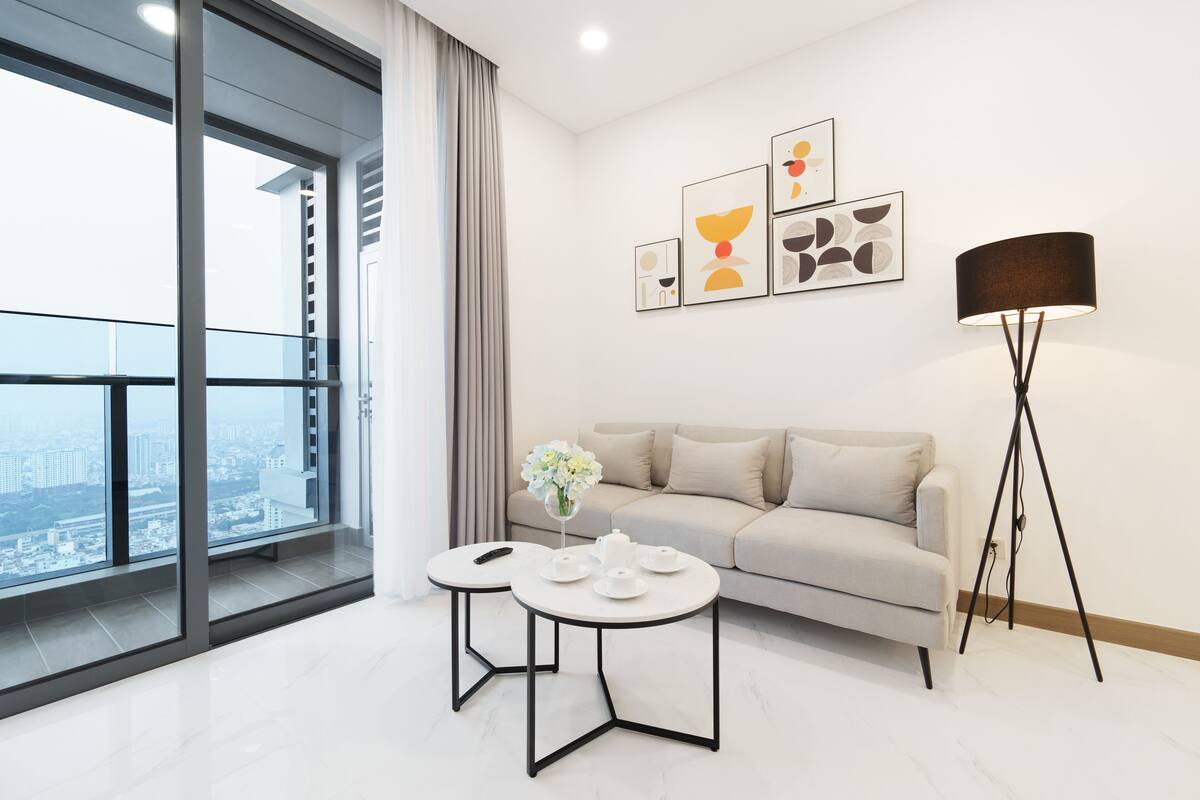 A modern living room with a sofa, two round tables, a floor lamp, and artwork on the wall.