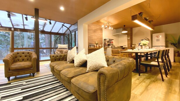 A spacious living area with a large sofa set, a dining table, and a kitchen in the background. - Diamond YU (Fujikawaguchiko)