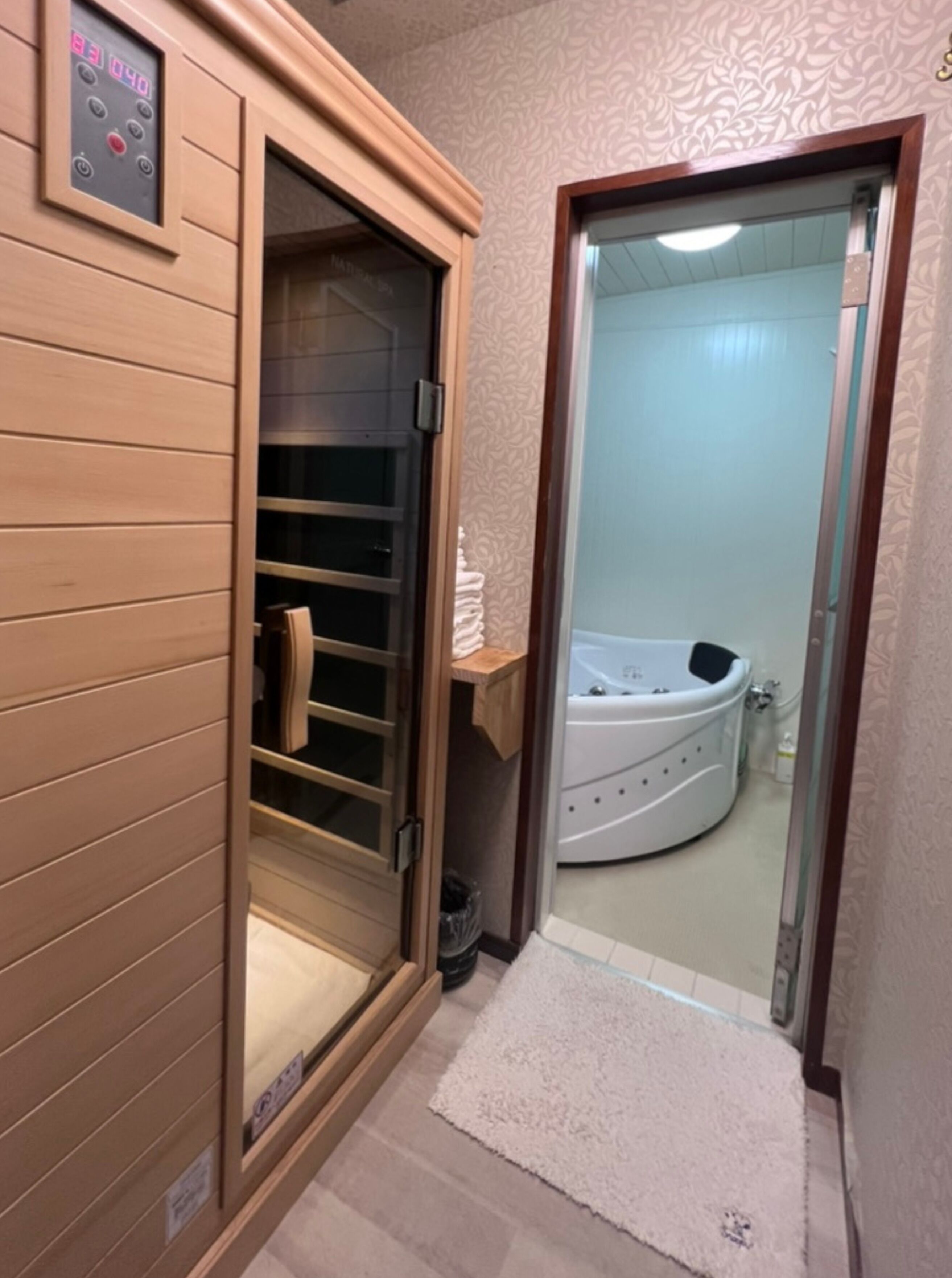 Un sauna con una puerta de madera y una puerta de cristal que da a un baño con bañera.