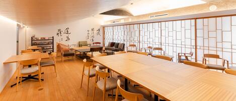 Una habitación amplia con una mesa de madera larga y varias sillas, una estantería y una pared con paneles decorativos.