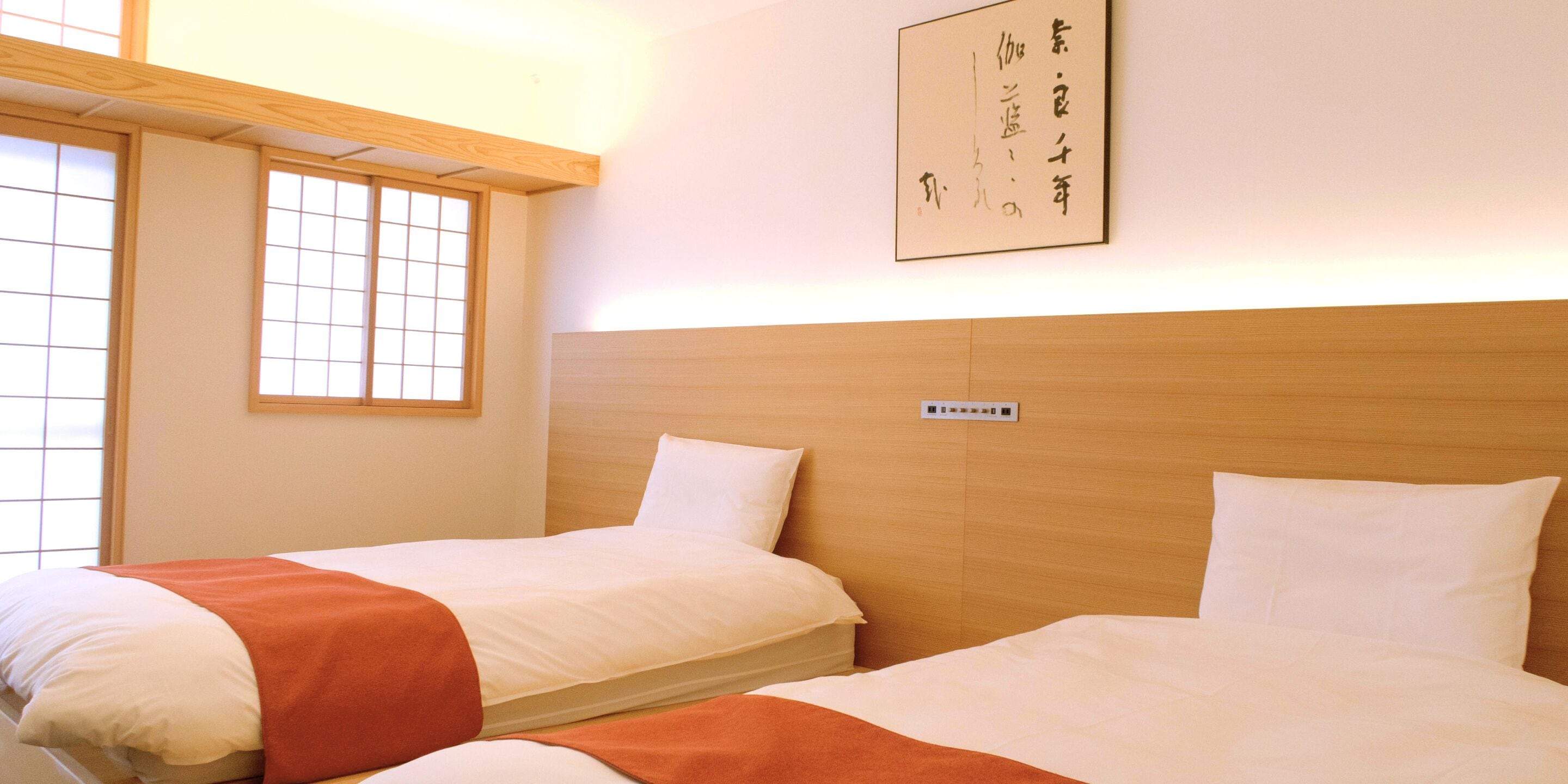 Une chambre d’hôtel avec deux lits, une tête de lit en bois, une fenêtre à carreaux et un panneau fixé au mur.