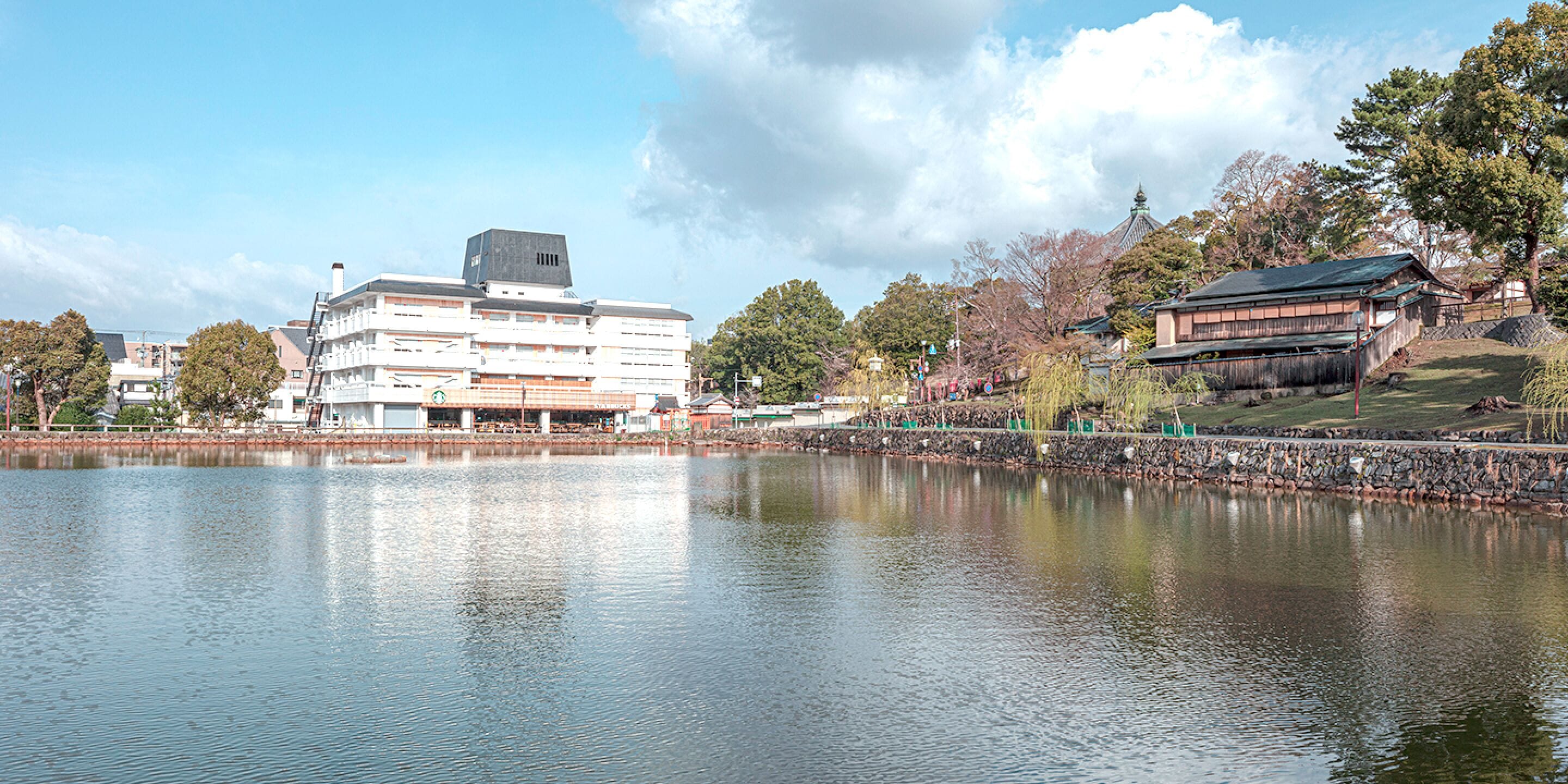 A building with multiple floors and a flat roof, situated next to a calm body of water.
