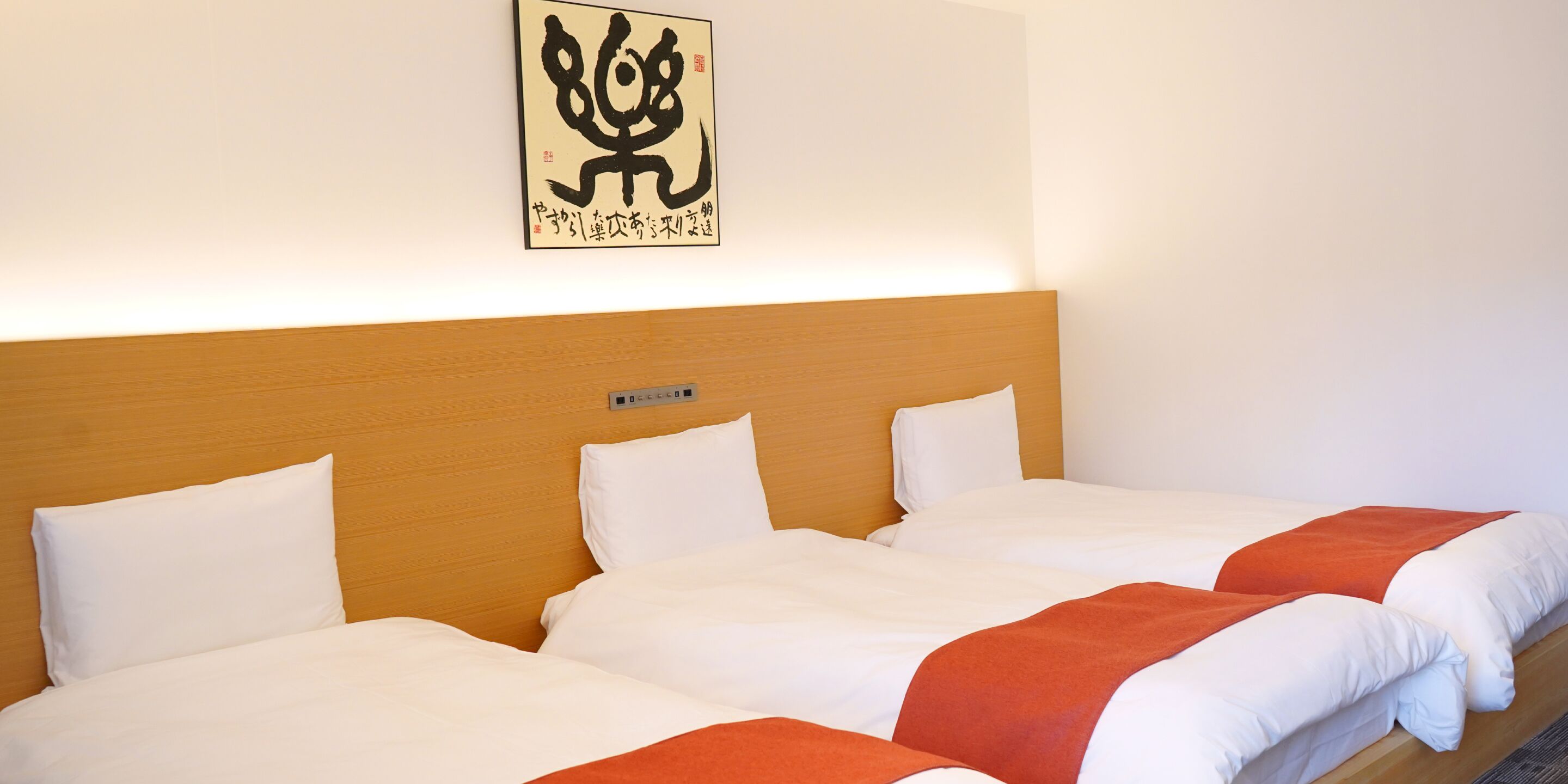 A hotel room with two beds, white bedding, a wooden headboard, and a wall-mounted artwork.