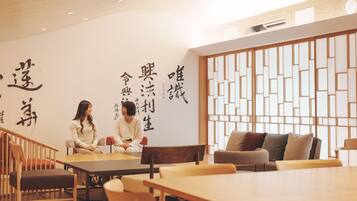 A room with a wooden table and chairs, a white wall with black calligraphy, and a traditional wooden screen.